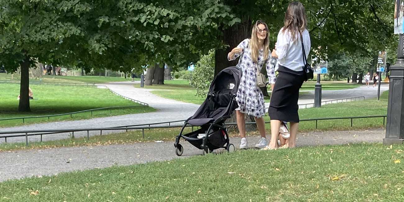 Vi ser prinsessan Sofia i en svartvit sommarklänning, hon står i en park med solglasögon på sig och talar engagerat med en väninna. Prins Julian och en barnvagn syns också på bilden.